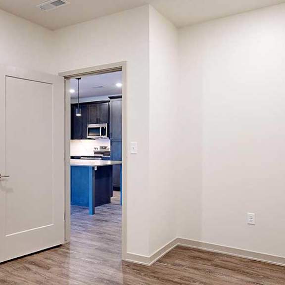 Thumbnail 17 of 28 a den space with hardwood flooring, white walls, and a door to the kitchen