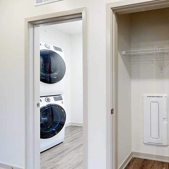Thumbnail 14 of 28 a coat closet in the front entryway next to a laundry room with a stackable washer and dryer