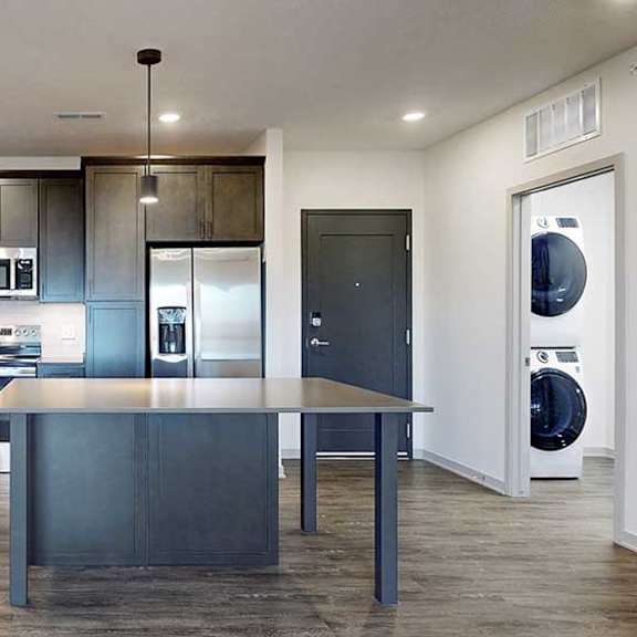 Thumbnail 5 of 28 a modern kitchen with dark wood cabinets, light quartz countertops, a tile backsplash, a large central island, and stainless steel appliances