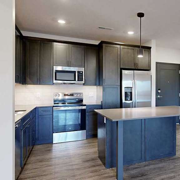 Thumbnail 13 of 28 a modern kitchen with dark wood cabinets and a central island next to a front door and laundry room