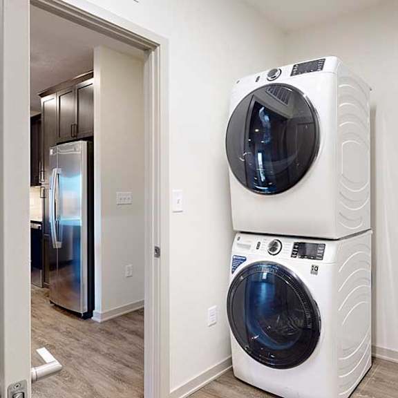 Thumbnail 15 of 28 a laundry room with a stackable washer and dryer next to the front door