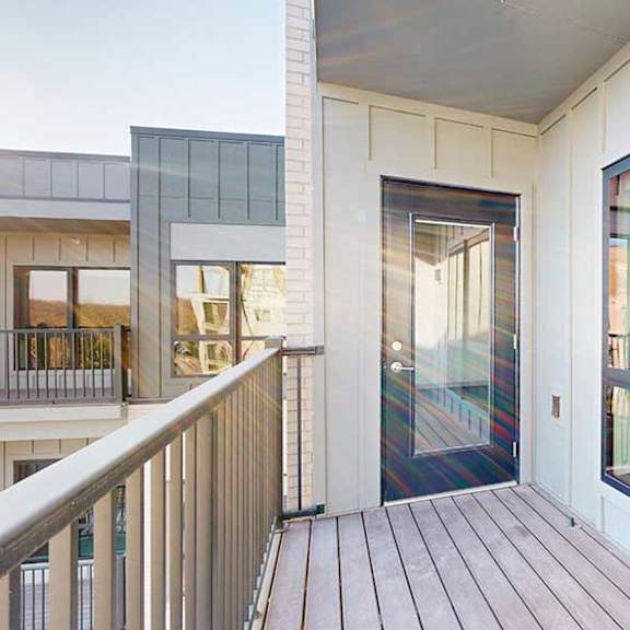 Thumbnail 14 of 24 A balcony with a metal railing, a windowed door to the living room, and a view of the courtyard.