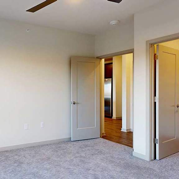 Thumbnail 18 of 24 A bedroom with floor-to-ceiling windows, a ceiling fan, and a walk-in closet.