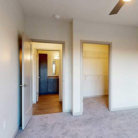 Thumbnail 20 of 24 A bedroom with a ceiling fan and a walk-in closet.