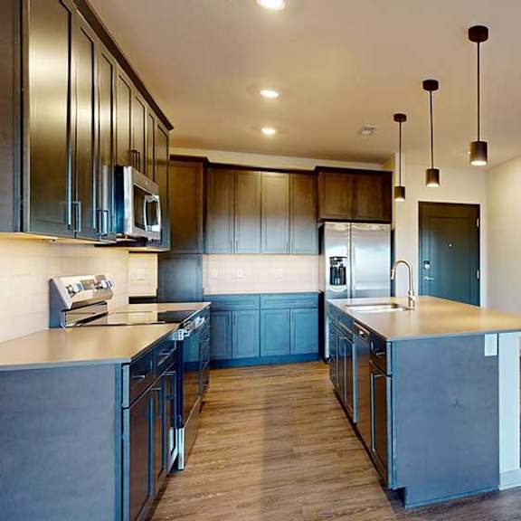 Thumbnail 2 of 24 A front entryway next to a modern kitchen with dark cabinets and stainless steel appliances.