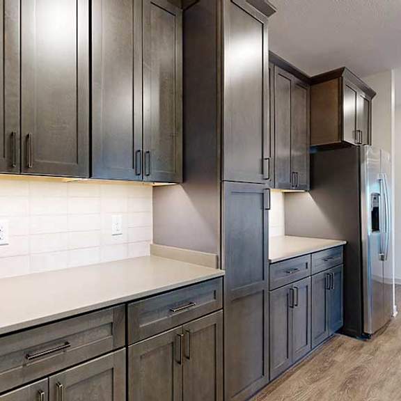 Thumbnail 5 of 24 A kitchen with dark wooden cabinets, quartz countertops, an island, and stainless steel appliances.