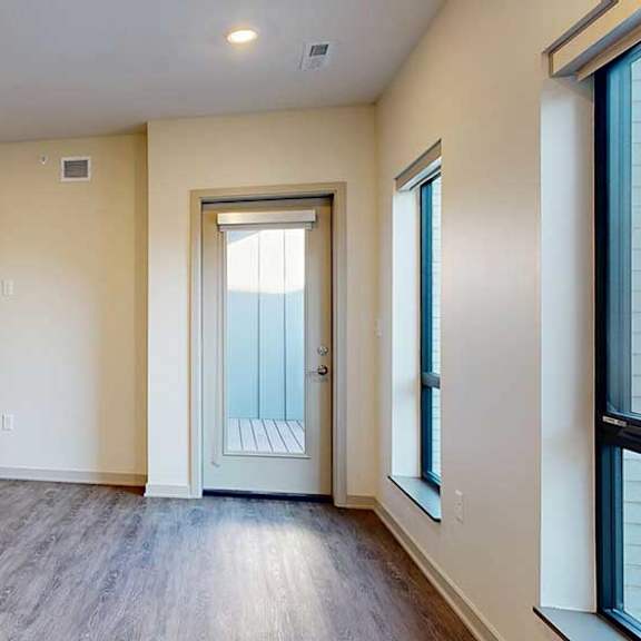 Thumbnail 12 of 24 A living room with hardwood-style flooring, floor-to-ceiling windows, and a windowed door to a balcony.