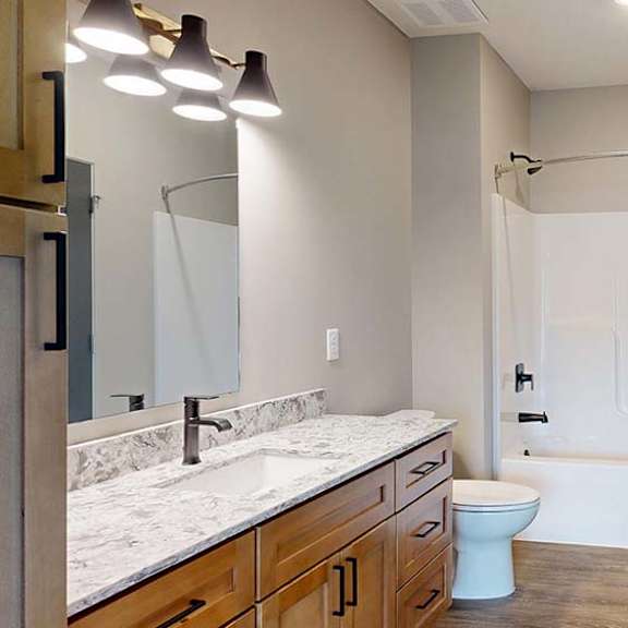 Thumbnail 67 of 84 Modern apartment bathroom with a tub and shower, single-sink vanity, and wood cabinetry.