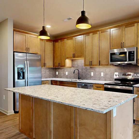 Thumbnail 54 of 84 Modern apartment kitchen with a large island, wood cabinetry, and stainless steel appliances.
