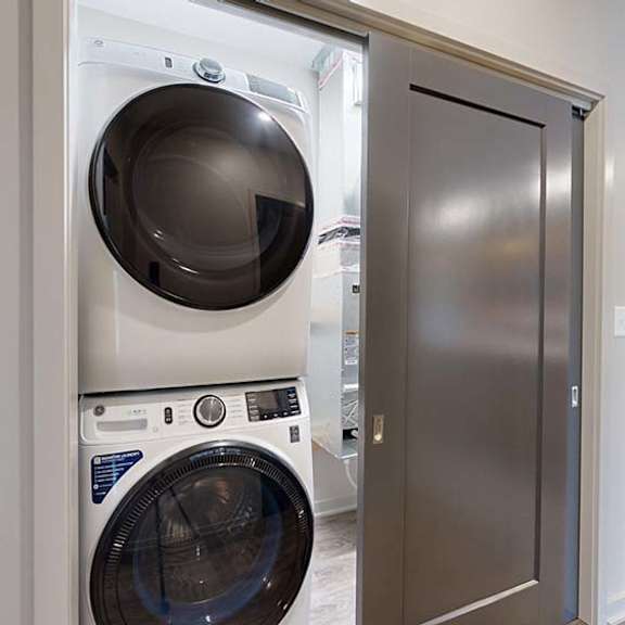 Thumbnail 63 of 84 Apartment laundry closet with a stacked washer and dryer next to the kitchen.