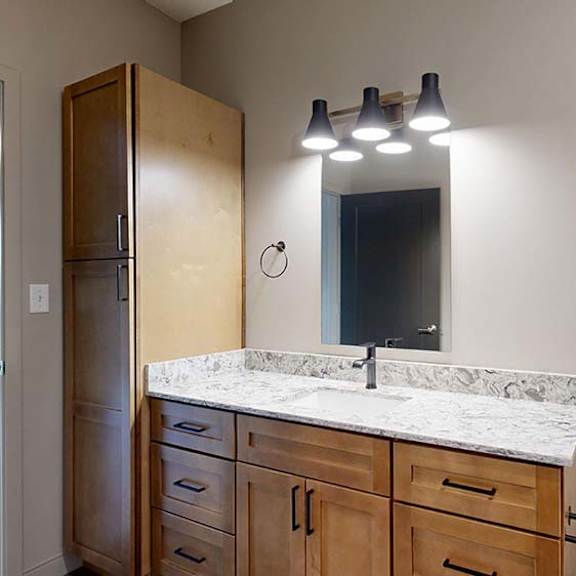 Thumbnail 51 of 84 Modern apartment bathroom with a single-sink vanity, wood cabinetry, and a large mirror.