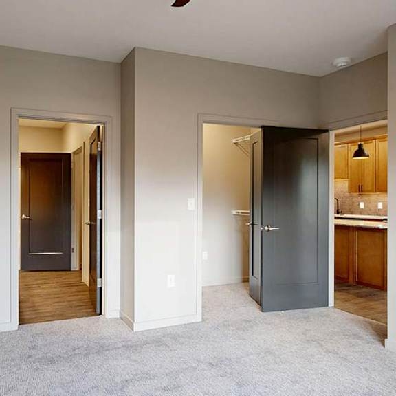 Thumbnail 49 of 84 Bright apartment bedroom with carpeted flooring and open doorways to the hallway and bathroom.