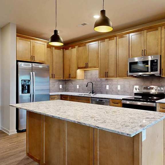 Thumbnail 40 of 84 Modern apartment kitchen with a large island, wood cabinetry, and stainless steel appliances.
