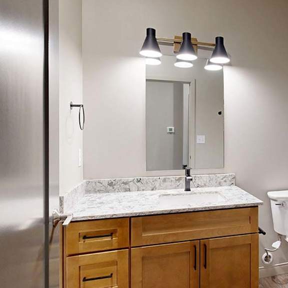 Thumbnail 35 of 36 Modern apartment bathroom with a single-sink vanity, wood cabinetry, and a large mirror.