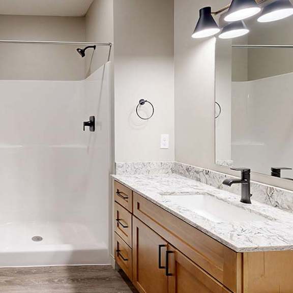 Thumbnail 34 of 36 Modern apartment bathroom with a tub and shower, single-sink vanity, and wood cabinetry.