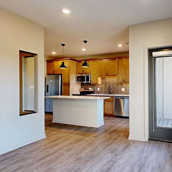 Thumbnail 29 of 36 Modern apartment kitchen with a large island, wood cabinetry, and stainless steel appliances.