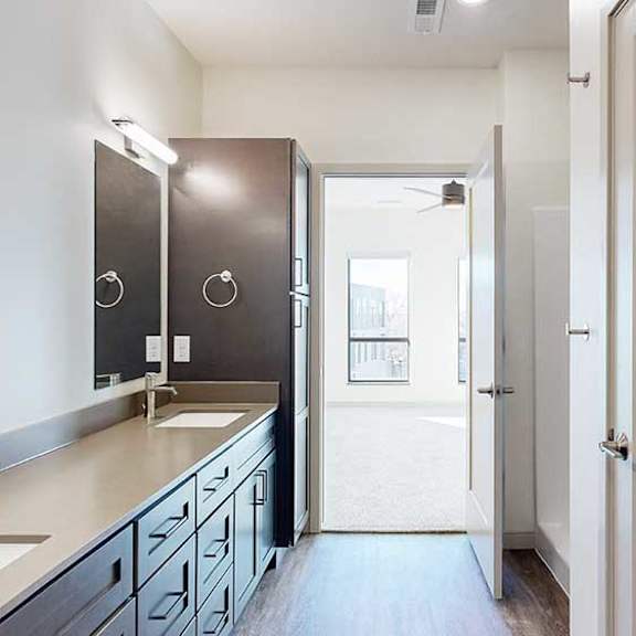 Thumbnail 22 of 30 a bathroom with a double quartz vanity sink, two mirrors, and a door to a bedroom