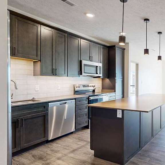 Thumbnail 8 of 30 a modern kitchen with a large central island, dark wood cabinets, and stainless steel appliances
