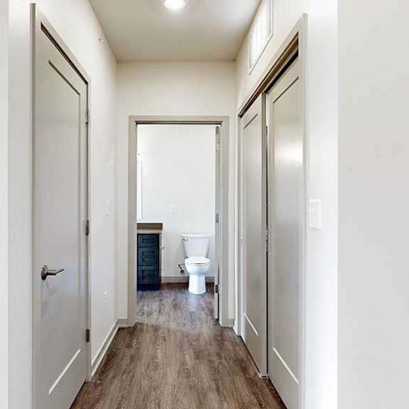 Thumbnail 25 of 30 a hallway with an entry closet, a laundry closet, and a door to a bathroom