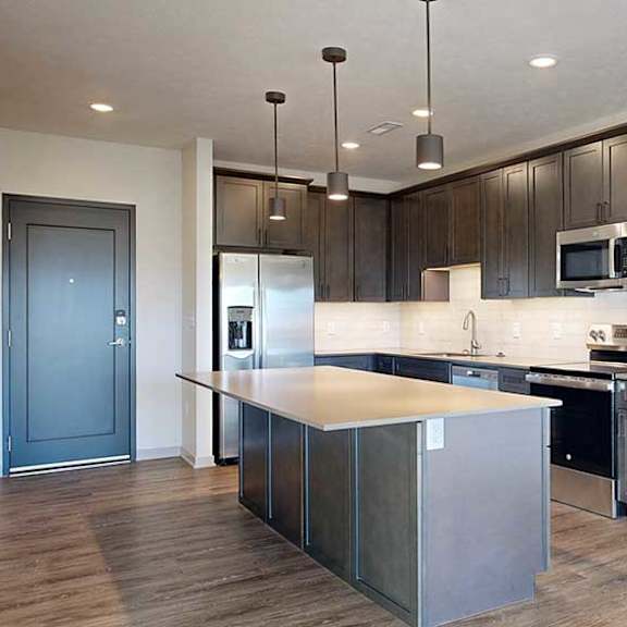 Thumbnail 4 of 30 a modern kitchen with dark wood cabinets, an island, stainless steel appliances, quartz countertops, and a tile backsplash