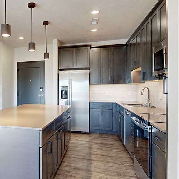 Thumbnail 3 of 30 a kitchen with a large central island with dark wooden cabinets and stainless steel appliances