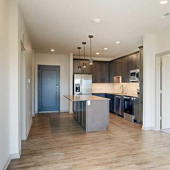 Thumbnail 14 of 30 a living room with hardwood flooring and a kitchen with dark wood cabinets