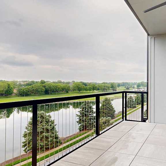 Thumbnail 23 of 46 A balcony with a windowed-door to the kitchen, tiled flooring, a metal railing, a ceiling fan, and a stunning view of the neighboring golf course.