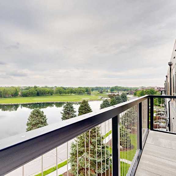 Thumbnail 22 of 46 An oversized balcony with a metal railing overlooking the neighboring pond.
