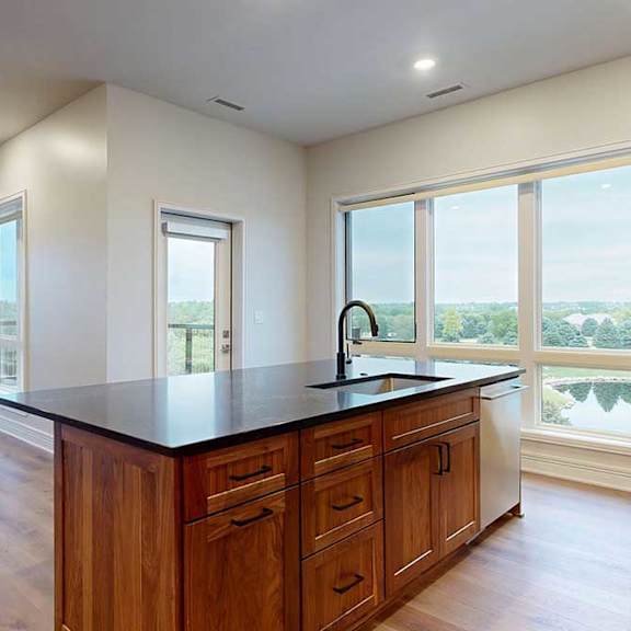 Thumbnail 19 of 46 A gourmet kitchen island with quartz countertops, overlooking a living room and dining area with floor-to-ceiling windows.