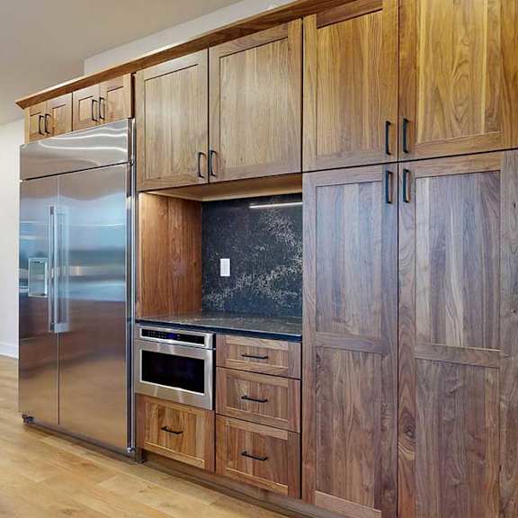 Thumbnail 16 of 46 A gourmet kitchen with an oversized stainless steel fridge, two stainless steel ovens, and oak wooden cabinets.