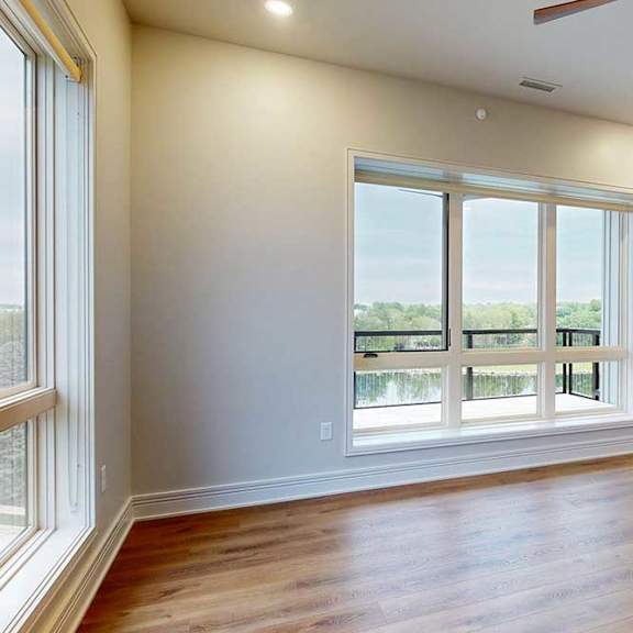 Thumbnail 24 of 46 A spacious living room with floor-to-ceiling windows and hardwood flooring, open to a gourmet kitchen.