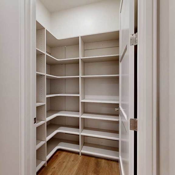Thumbnail 18 of 46 A walk-in pantry with built-in wooden shelves.