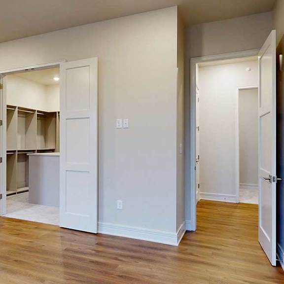 Thumbnail 34 of 46 A bedroom with a walk-in boutique-style closet, and hardwood flooring.