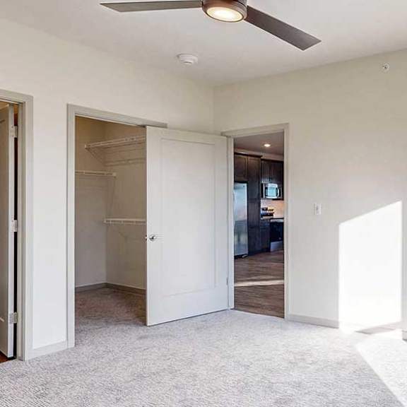 Thumbnail 17 of 33 a bedroom with a carpeted floor, a ceiling fan, a large window, and a spacious walk-in closet