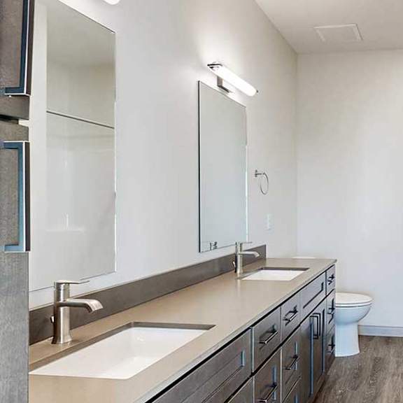Thumbnail 22 of 33 a bathroom with a quartz double vanity sink, a mirror with overhead lighting, and a walk-in shower