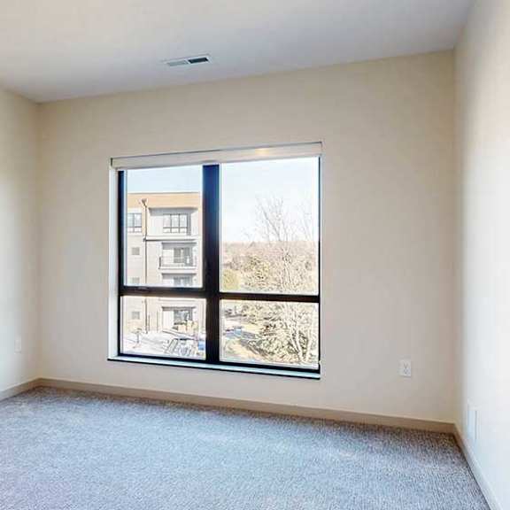 Thumbnail 26 of 33 a bedroom with a carpeted floor and a large window looking out to the courtyard