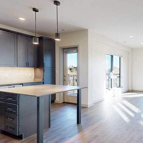 Thumbnail 13 of 33 a spacious living room with large windows and a modern kitchen with dark wooden cabinets