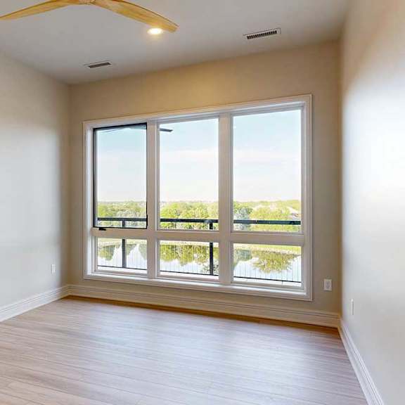 Thumbnail 27 of 31 A bedroom with a large window and wooden flooring.