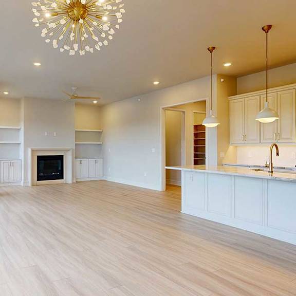 Thumbnail 13 of 31 A spacious living room with a fireplace and a kitchen area in the background.