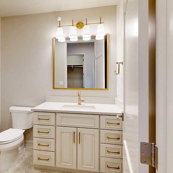 Thumbnail 3 of 31 Penthouse hall bathroom with white cabinets, marble tile floors, and gold hardware finishes
