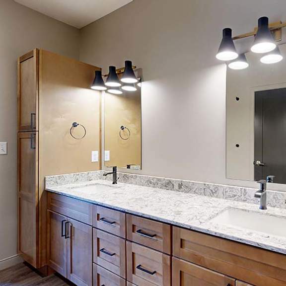Thumbnail 42 of 46 Modern apartment bathroom with a double-sink vanity, wood cabinetry, quartz-style countertop, large mirror, and contemporary wall-mounted lighting.