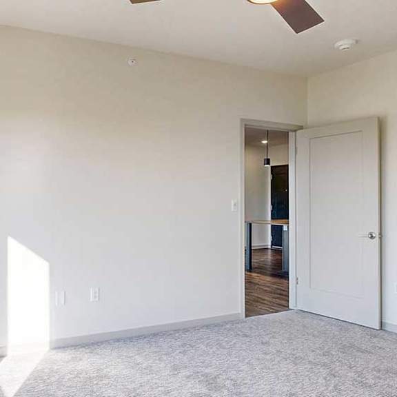 Thumbnail 17 of 30 a bedroom with a window shining in, carpeted flooring, and a ceiling fan