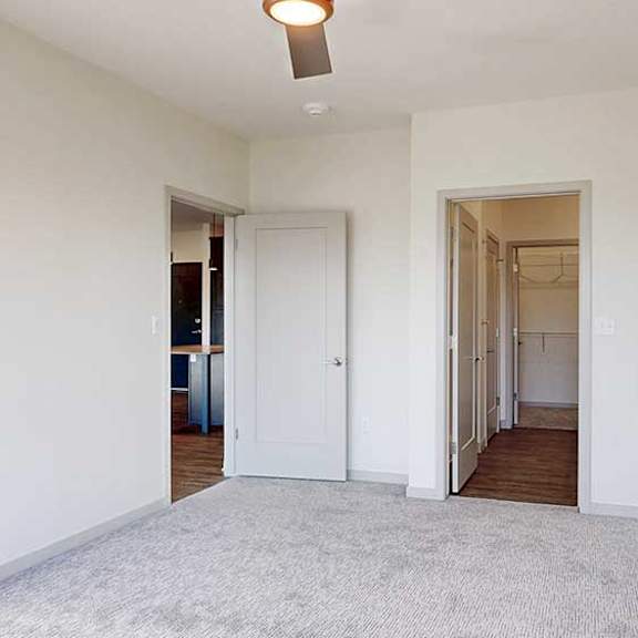 Thumbnail 16 of 30 a bedroom with carpeted flooring, an attached bathroom, and a walk-in closet connected via the bathroom