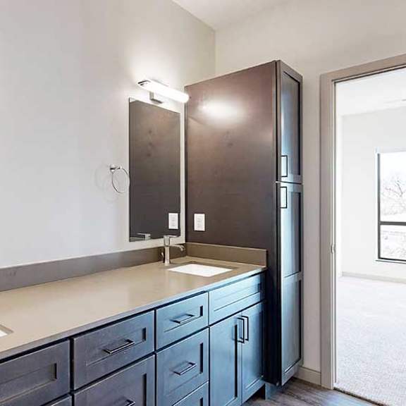 Thumbnail 19 of 30 a bathroom with a double vanity sink, two mirrors, and a tall dark wooden storage cabinet