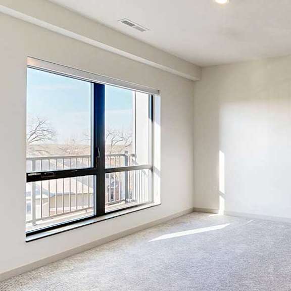 Thumbnail 23 of 30 a bedroom with carpeted flooring and a window looking out to a balcony