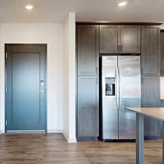 Thumbnail 2 of 30 a grey front door next to a modern kitchen with dark cabinets and stainless steel appliances