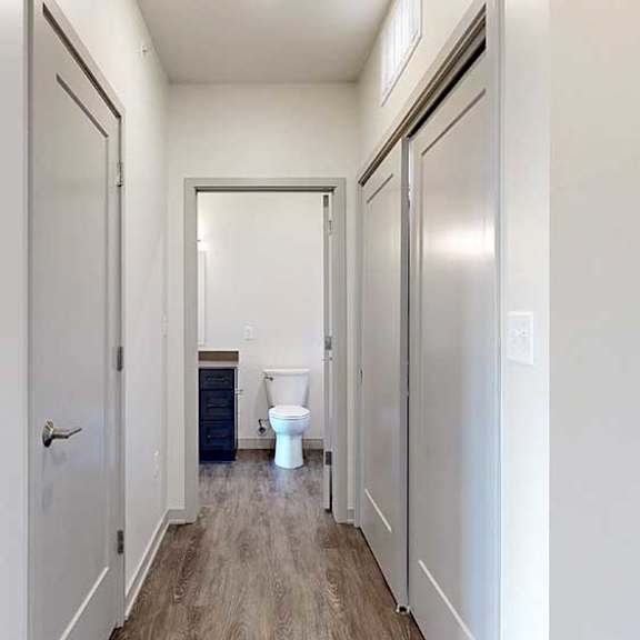 Thumbnail 28 of 30 a hallway with two closets and an open door to a bathroom