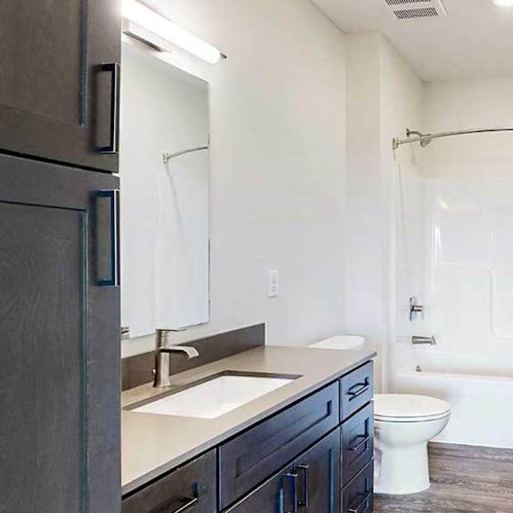 Thumbnail 27 of 30 a bathroom with a dark cabinet quartz vanity sink and a combo shower tub