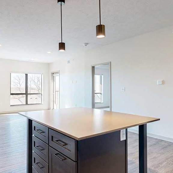 Thumbnail 9 of 30 a kitchen table island with dark cabinets and quartz cabinets in front of a spacious living room
