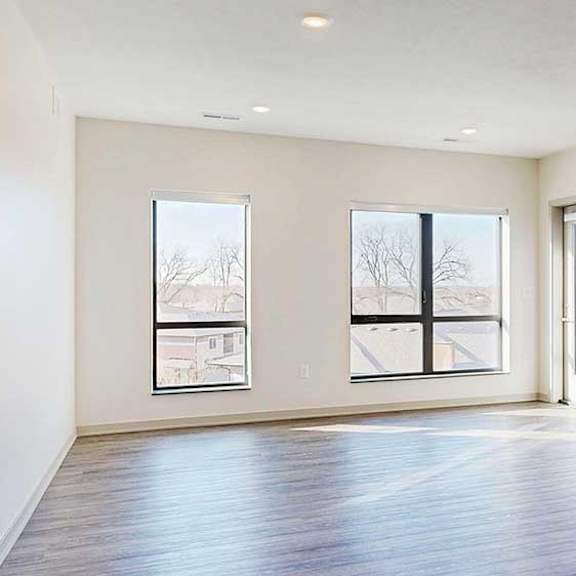 Thumbnail 10 of 30 a spacious living room with two large windows, hardwood flooring, and a windowed door to a balcony
